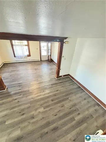 a view of an empty room with wooden floor and a window