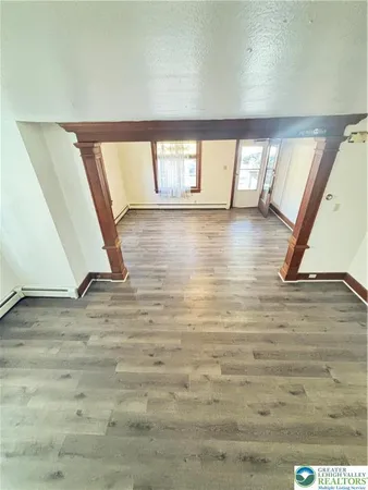 a view of an empty room with wooden floor and window