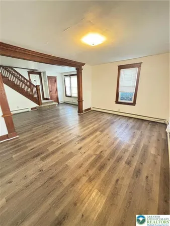 a view of an empty room with window and wooden floor
