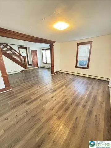 a view of an empty room with window and wooden floor