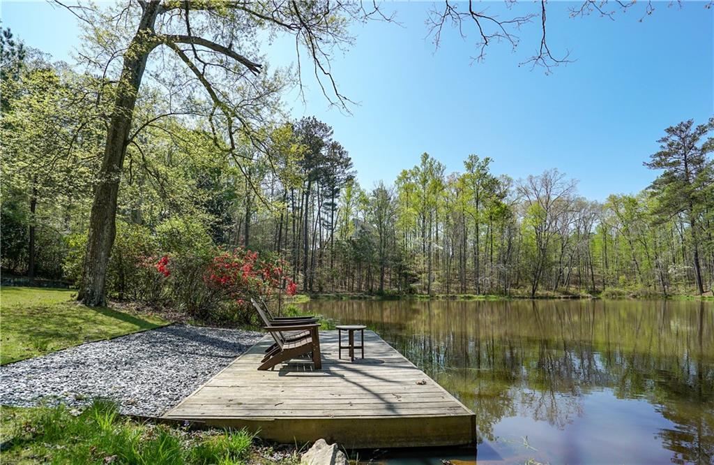 13565 Wood Fern Way Roswell, GA 30075 - Photo 8 of 14 a view of a lake with a bench under large trees