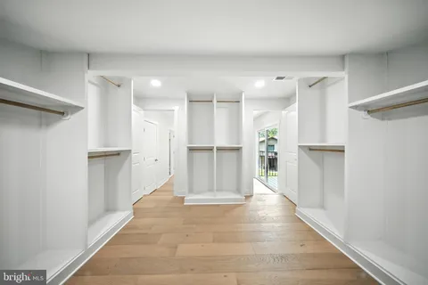 a view of an empty room with wooden floor and a kitchen