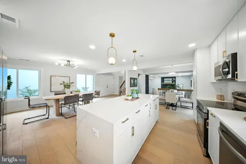 a large living room with stainless steel appliances kitchen island granite countertop a large kitchen island a stove a sink a dining table and chairs with wooden floor