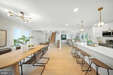 a room with stainless steel appliances kitchen island granite countertop lots of wooden furniture dining table and chairs