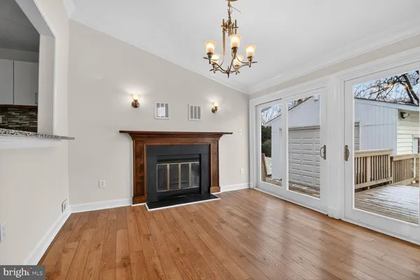 a view of an empty room with wooden floor fireplace and a window