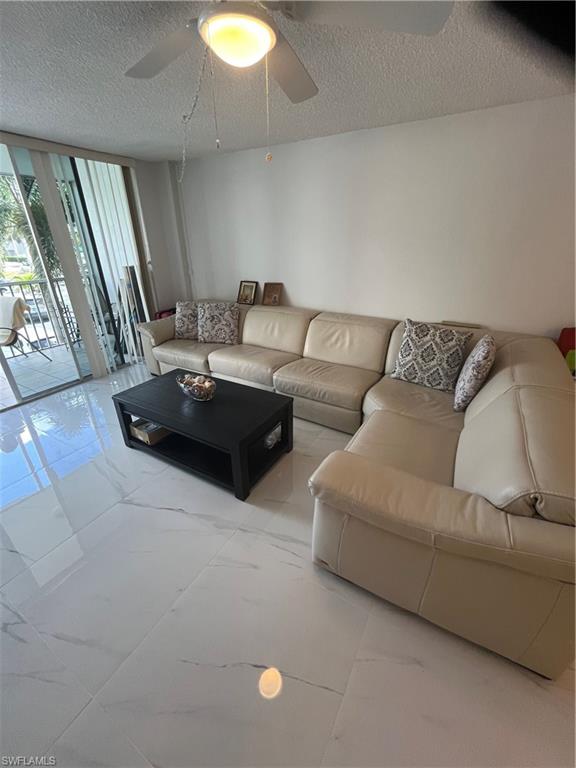 3 Bluebill Avenue, Unit 207 Naples, FL 34108 - Photo 11 of 27 Living room with floor to ceiling windows, a textured ceiling, and ceiling fan
