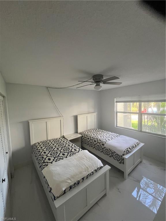 3 Bluebill Avenue, Unit 207 Naples, FL 34108 - Photo 14 of 27 Bedroom with marble look tile flooring, a ceiling fan, and a closet