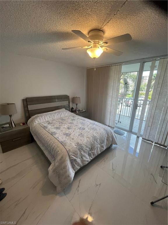 3 Bluebill Avenue, Unit 207 Naples, FL 34108 - Photo 15 of 27 Bedroom featuring access to exterior, a textured ceiling, a ceiling fan, and expansive windows