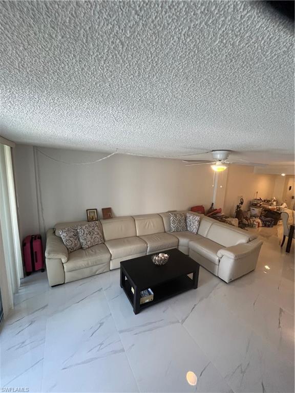 3 Bluebill Avenue, Unit 207 Naples, FL 34108 - Photo 18 of 27 Living room with ceiling fan, a textured ceiling, and light marble finish flooring