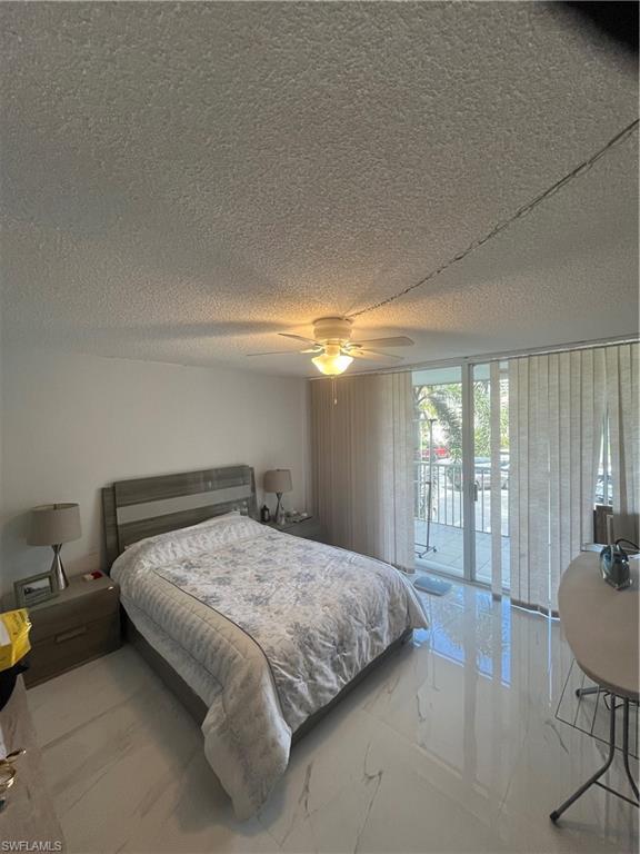 3 Bluebill Avenue, Unit 207 Naples, FL 34108 - Photo 20 of 27 Bedroom featuring access to outside, ceiling fan, a textured ceiling, and expansive windows
