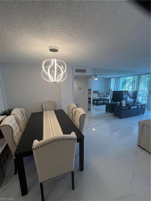 3 Bluebill Avenue, Unit 207 Naples, FL 34108 - Photo 23 of 27 Dining area featuring a textured ceiling and hanging lights