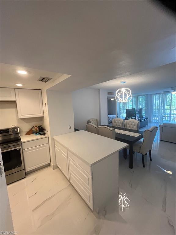 3 Bluebill Avenue, Unit 207 Naples, FL 34108 - Photo 27 of 27 Kitchen with open floor plan, stove, white cabinetry, light countertops, and a peninsula