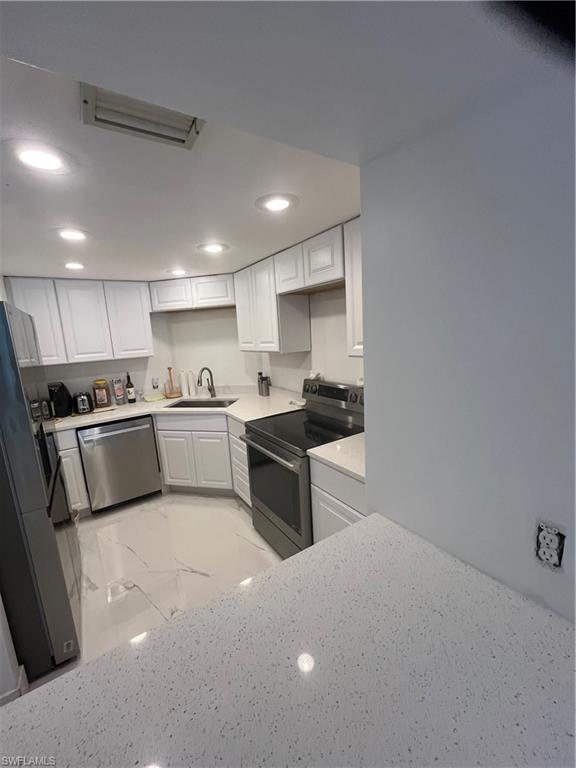 3 Bluebill Avenue, Unit 207 Naples, FL 34108 - Photo 24 of 27 Kitchen with range, white cabinets, light marble finish floors, fridge, and recessed lighting