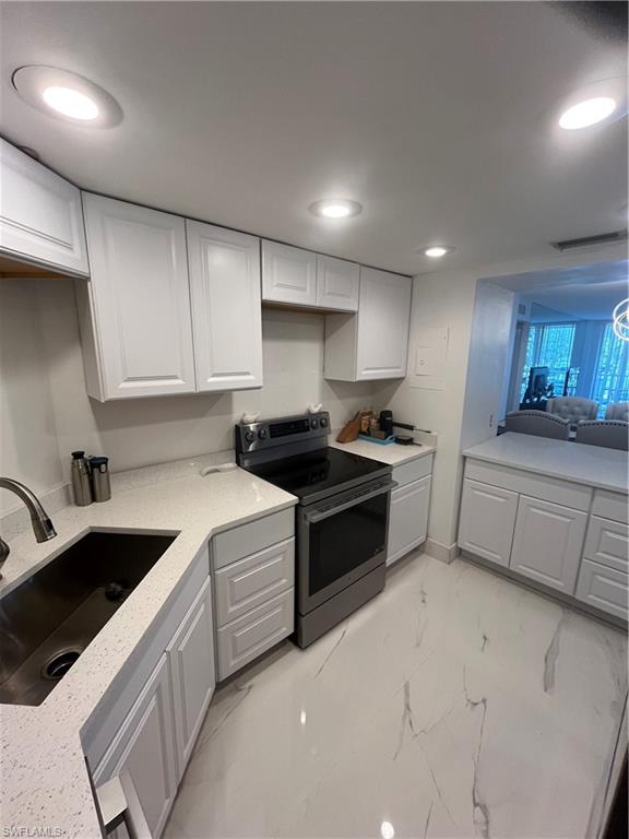 3 Bluebill Avenue, Unit 207 Naples, FL 34108 - Photo 25 of 27 Kitchen featuring stainless steel range, white cabinets, recessed lighting, light stone counters, and light marble finish flooring