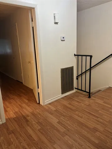 a view of an empty room with wooden floor and stairs