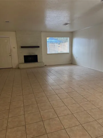 a view of an empty room with a fireplace and a window