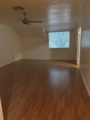 an empty room with wooden floor cabinet and windows