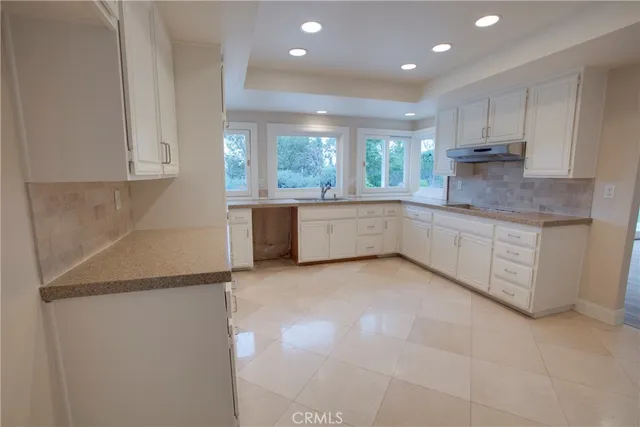 a kitchen with granite countertop a sink and white cabinets