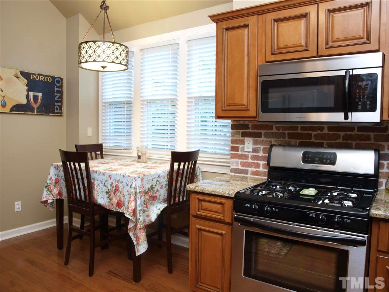 5729 Sentinel Drive Raleigh, NC 27609 - Photo 3 of 17 a kitchen with stainless steel appliances a stove a microwave a dining table and chairs