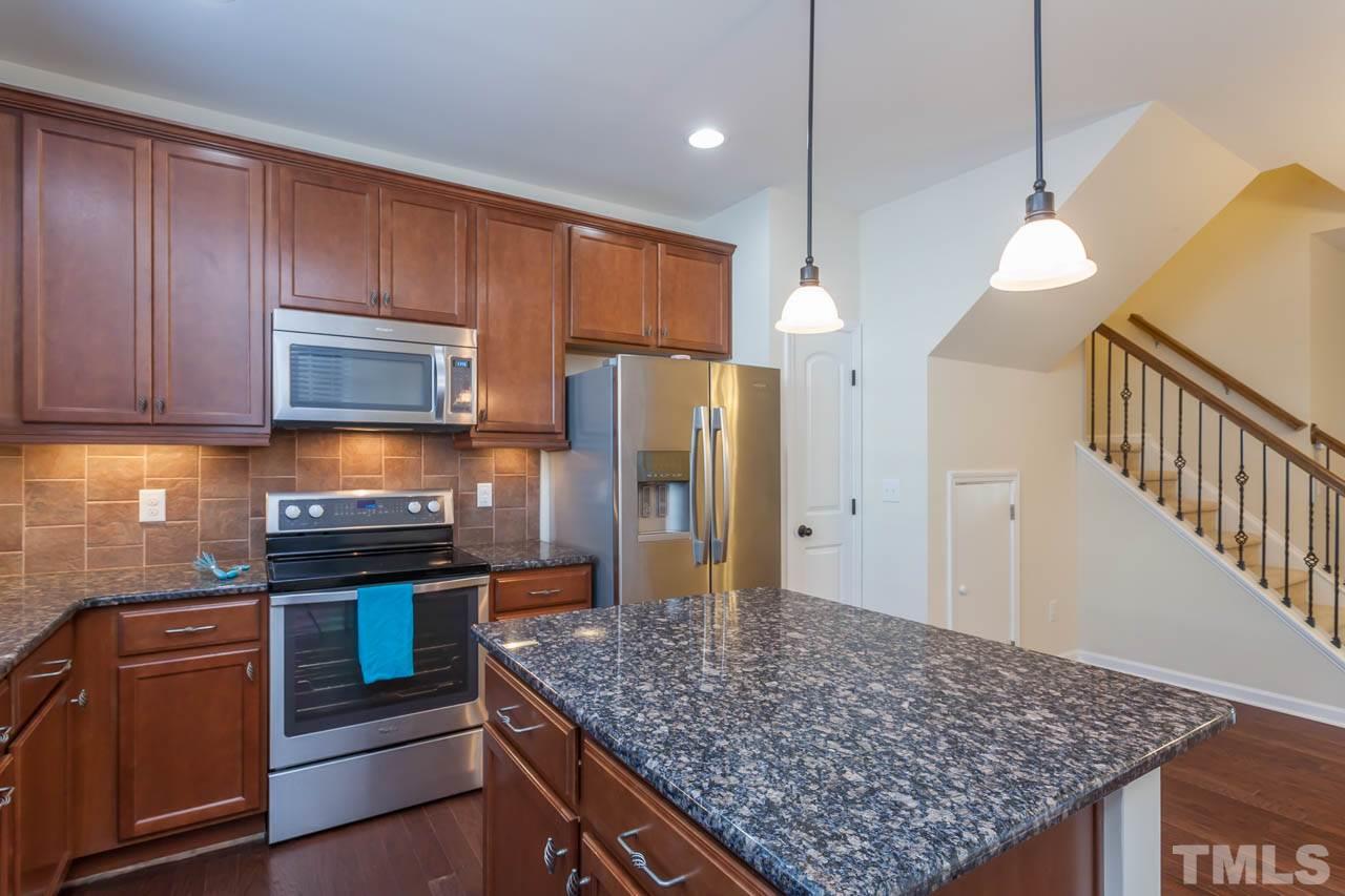 7326 Caversham Way Raleigh, NC 27617 - Photo 11 of 23 a kitchen with stainless steel appliances granite countertop a stove refrigerator and microwave
