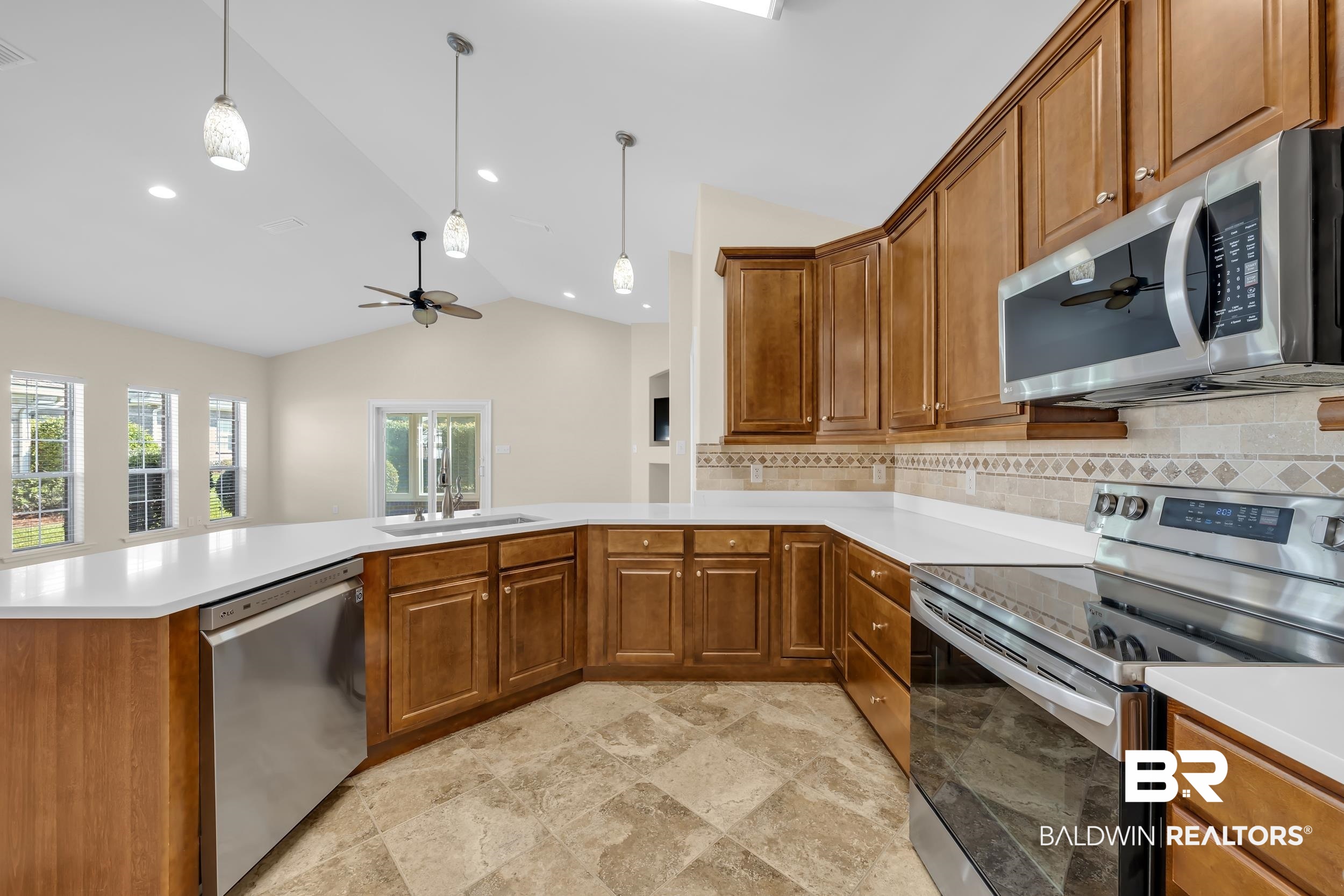 226 Hemingway Loop Foley, AL 36535 - Photo 6 of 53 Kitchen featuring brown cabinetry, stainless steel appliances, a ceiling fan, vaulted ceiling, and tasteful backsplash