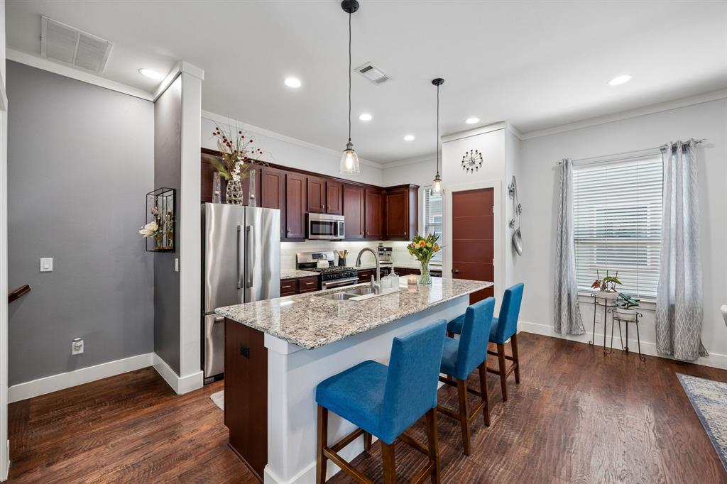 5875 Ross Avenue, Unit 9 Dallas, TX 75206 - Photo 6 of 29 Kitchen featuring stainless steel appliances, granite countertops, a kitchen bar, dark wood-style floors, pantry and ornamental molding