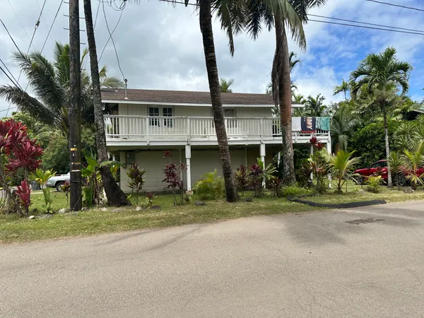 a front view of a house with a garden and trees