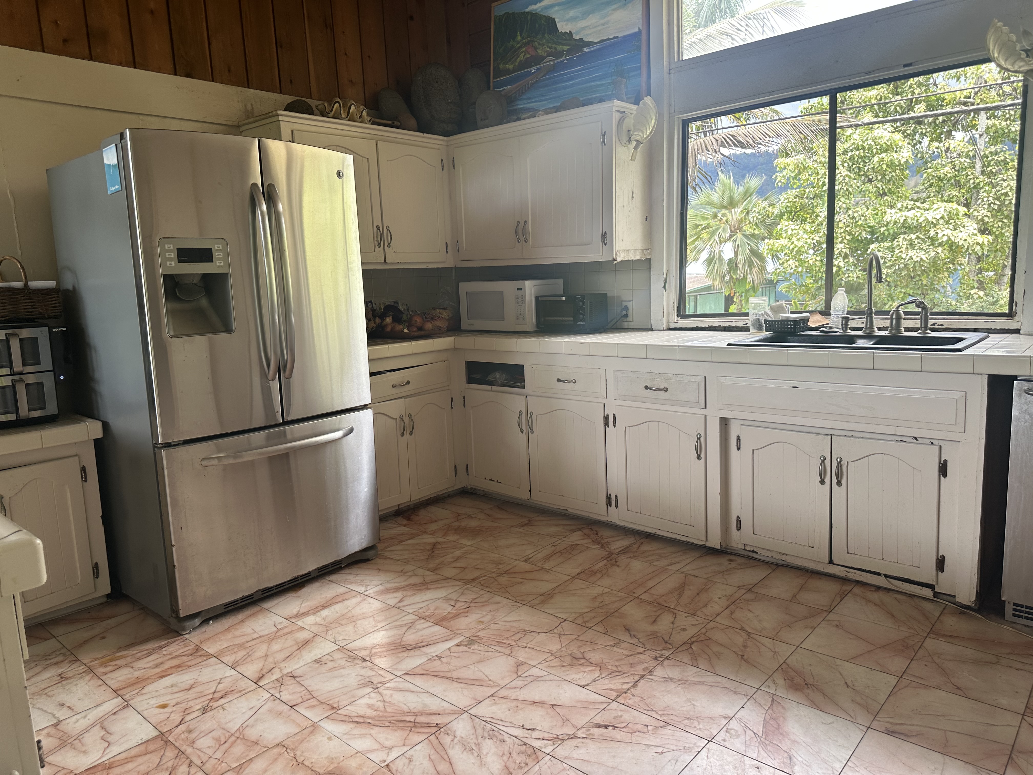 5404 Weke Road Hanalei, HI 96714 - Photo 18 of 19 a kitchen with white cabinets stainless steel appliances and a large window