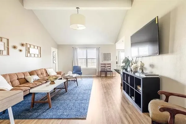 a living room with furniture a flat screen tv and kitchen view