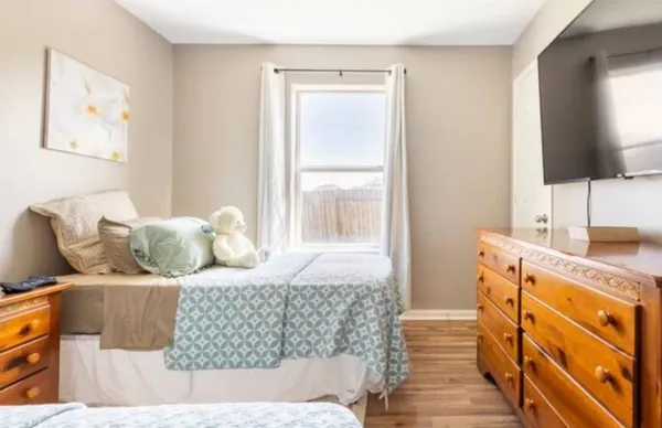 a bedroom with a large bed and a flat tv screen on dresser