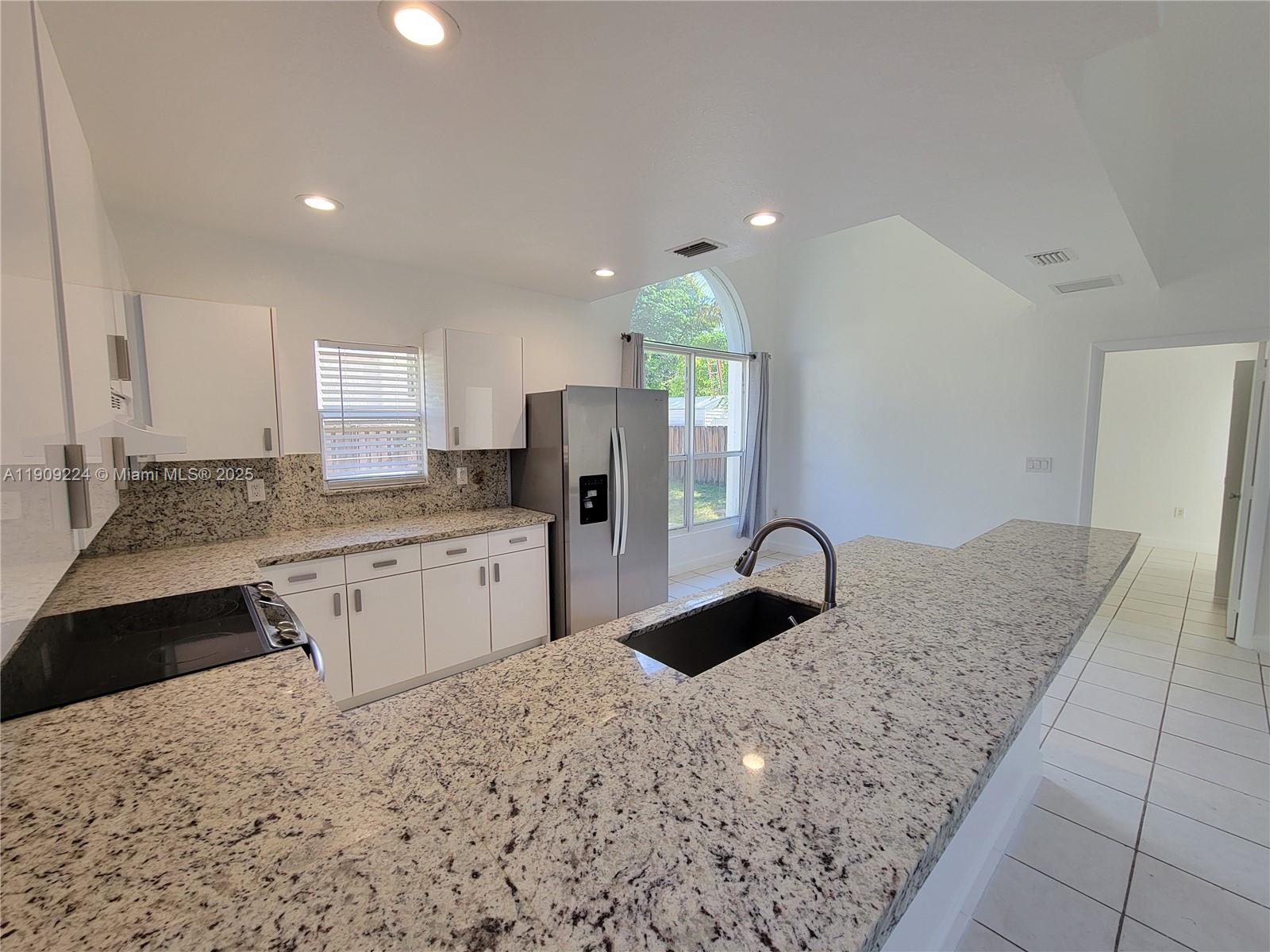 35 Southwest 7th Street, Unit 2 Hallandale Beach, FL 33009 - Photo 16 of 23 a kitchen with granite countertop a refrigerator and a sink