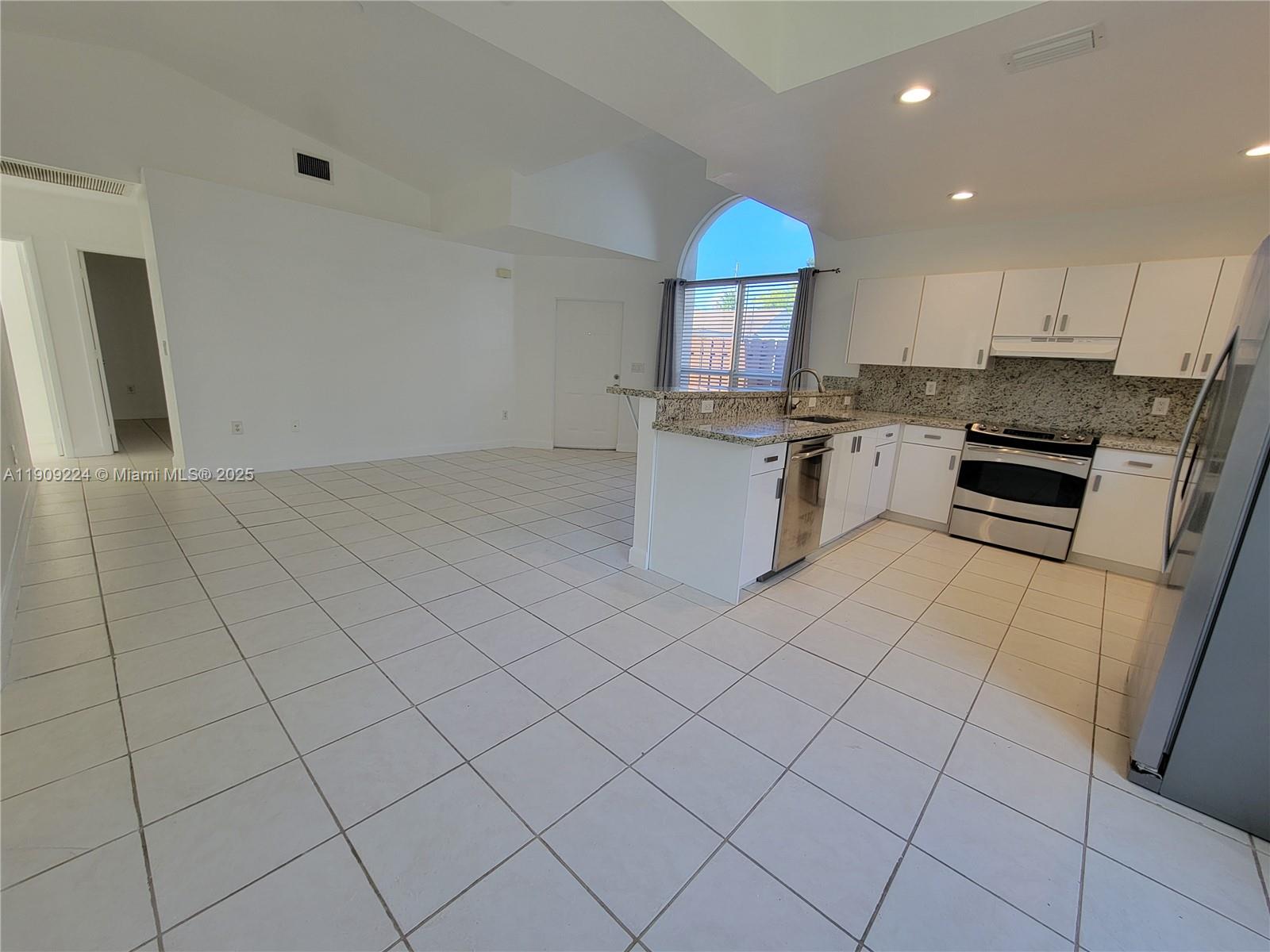 35 Southwest 7th Street, Unit 2 Hallandale Beach, FL 33009 - Photo 17 of 23 a kitchen with stainless steel appliances granite countertop a sink a stove a microwave a counter top space and cabinets