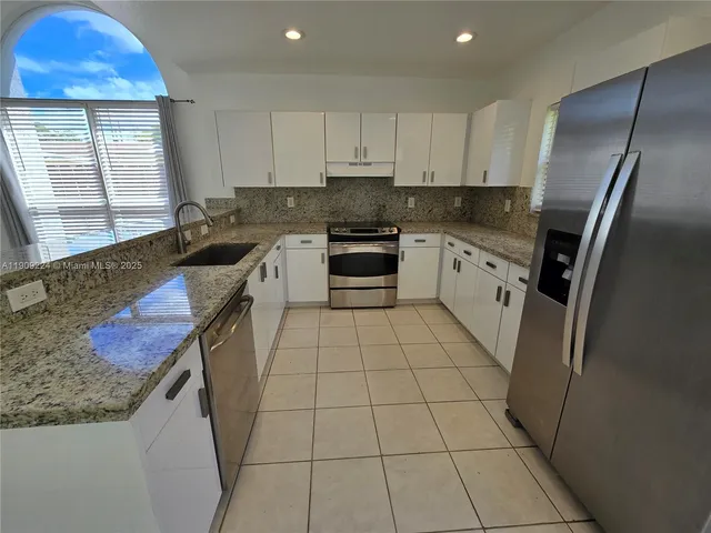 a kitchen with stainless steel appliances granite countertop a stove a sink and a refrigerator