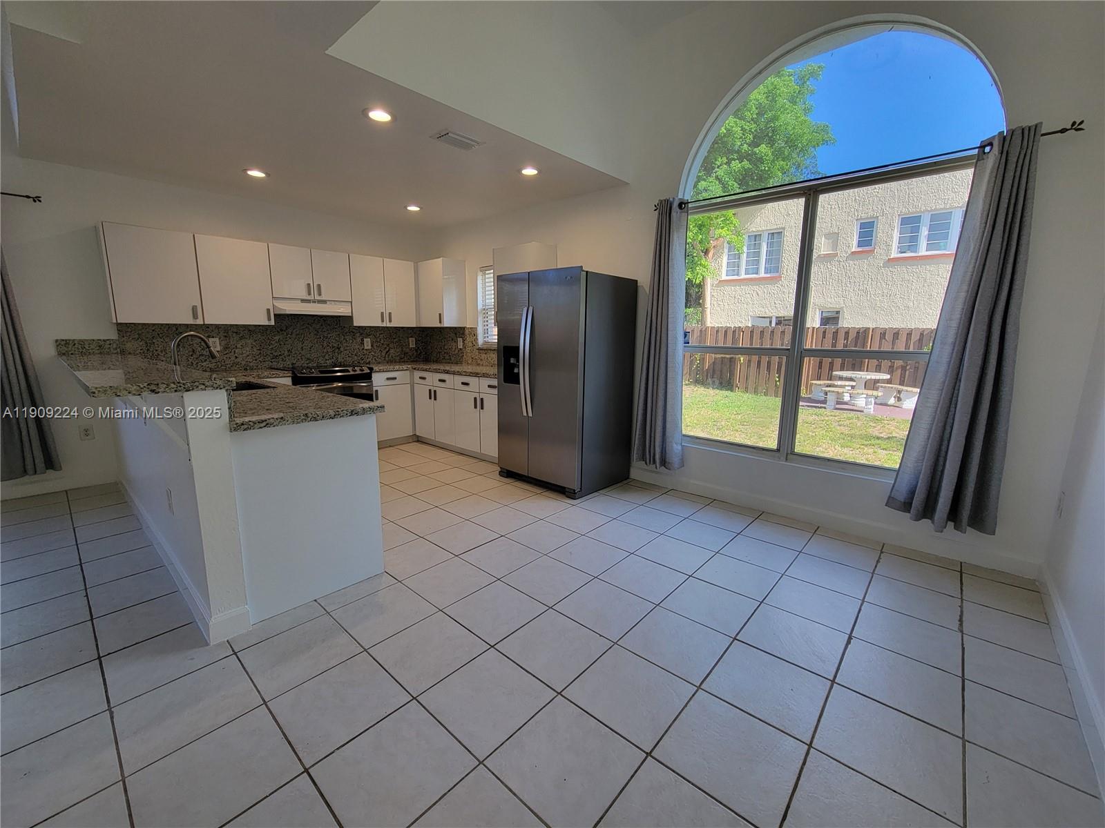 35 Southwest 7th Street, Unit 2 Hallandale Beach, FL 33009 - Photo 6 of 23 a kitchen with stainless steel appliances granite countertop a refrigerator a sink a stove top oven and a large window