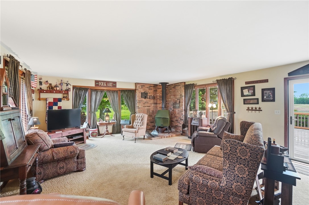 4170 Johnson Road Springfield, OH 45502 - Photo 15 of 54 A generous living area presents a cozy fireplace with brick surround, alongside large windows offering verdant outdoor views.