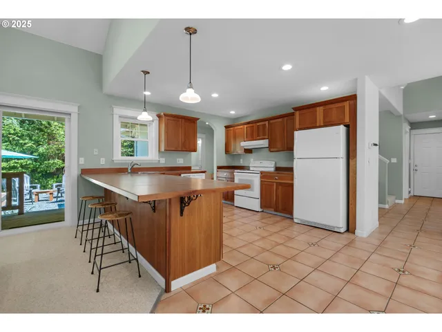 a open kitchen with stainless steel appliances granite countertop a refrigerator a sink a stove a dining table and chairs