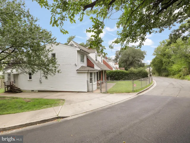 a view of a house with a small yard and large trees