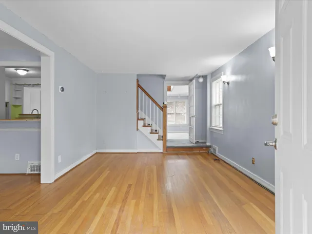 a view of an empty room with window and wooden floor
