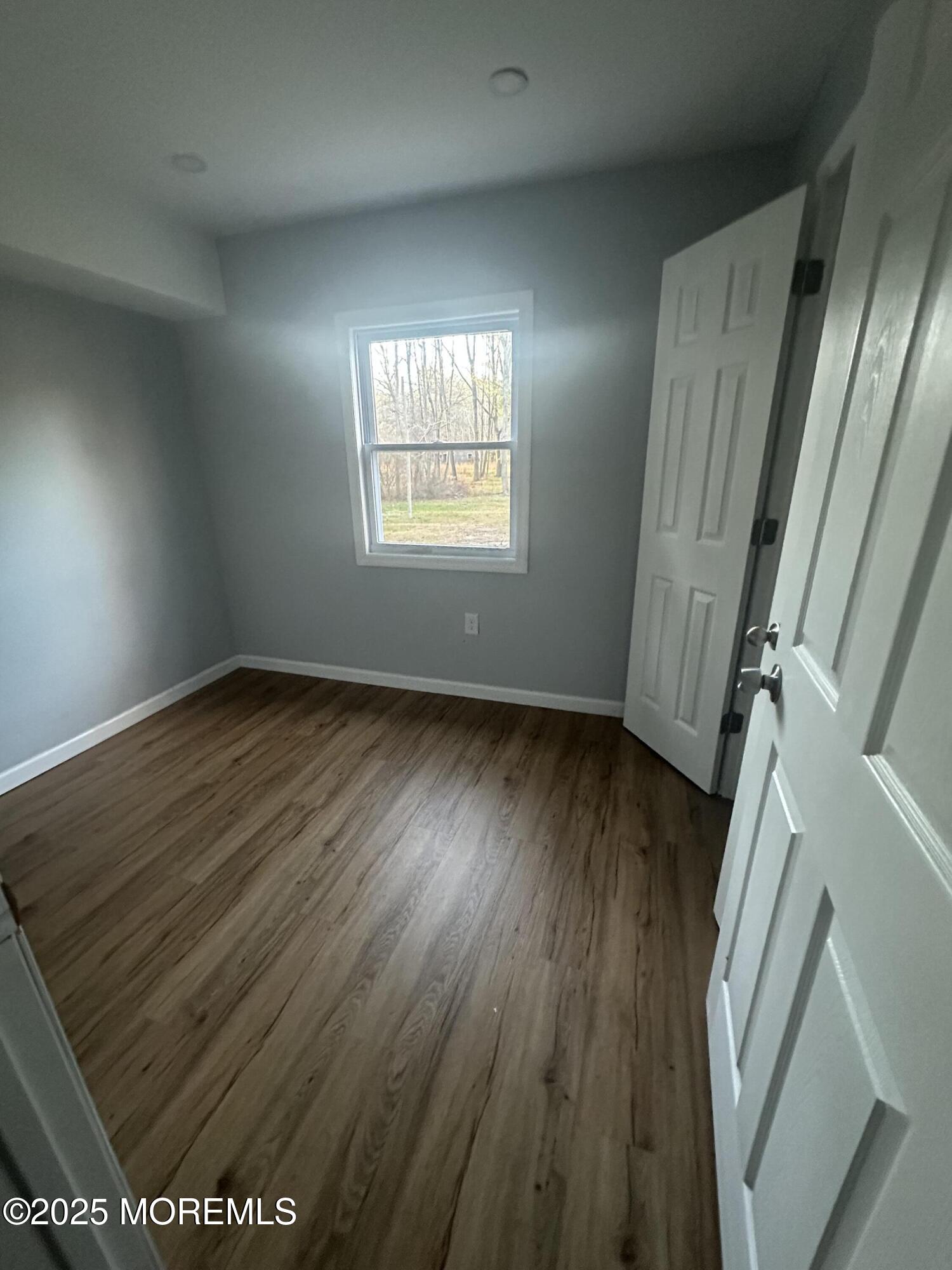 244 Perrineville Road Jackson, NJ 08527 - Photo 5 of 9 an empty room with wooden floor and windows