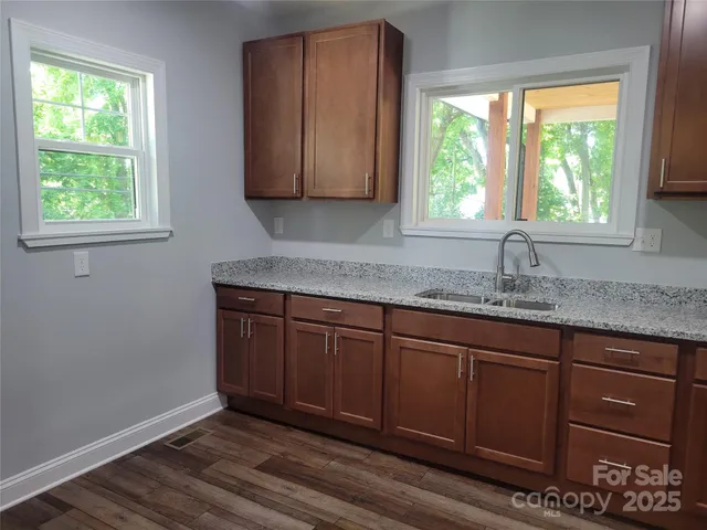 a kitchen with granite countertop wooden cabinets a sink and a window