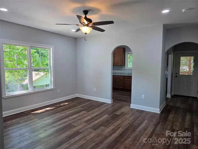 an empty room with wooden floor fan and windows