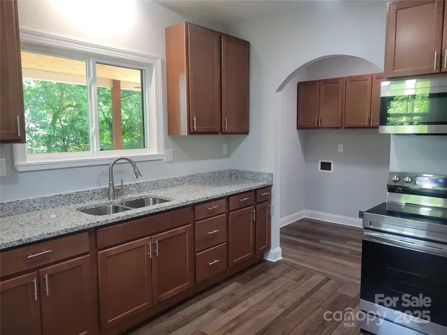 a kitchen with stainless steel appliances granite countertop a sink a stove and a wooden cabinets