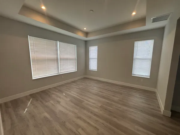 an empty room with wooden floor and windows
