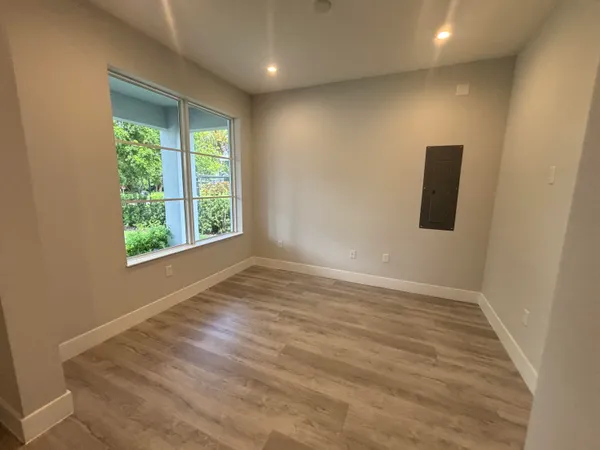 an empty room with wooden floor and windows