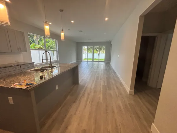 a kitchen with kitchen island granite countertop wooden floors wooden cabinets a sink and a window