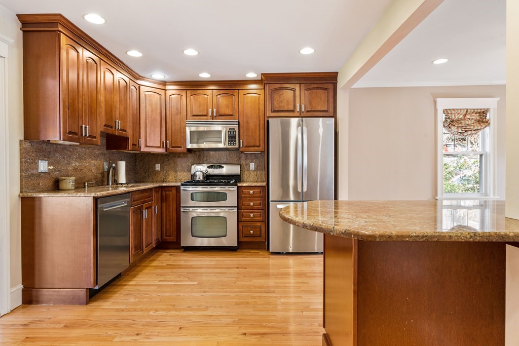 35 Lovell Road Watertown, MA 02472 - Photo 14 of 42 a kitchen with stainless steel appliances granite countertop a refrigerator a sink dishwasher a stove and white countertops with wooden floor