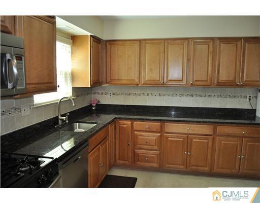 7104 Hana Road Edison, NJ 08817 - Photo 5 of 10 a kitchen with granite countertop a sink a stove and cabinets