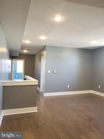 an empty room with kitchen view and a refrigerator