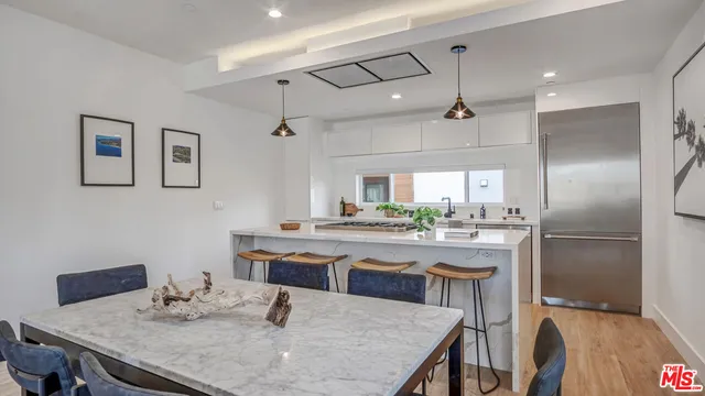 a kitchen with stainless steel appliances granite countertop a dining table chairs and refrigerator