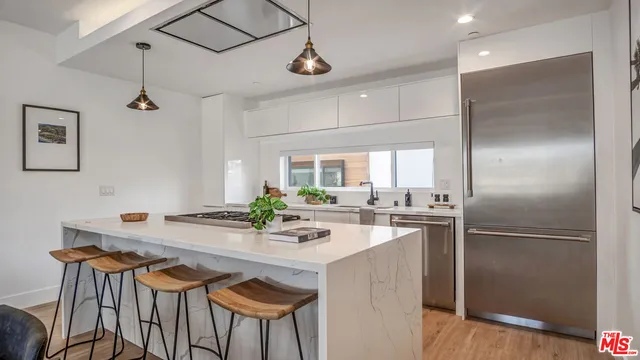 a kitchen with stainless steel appliances a dining table chairs and wooden floor